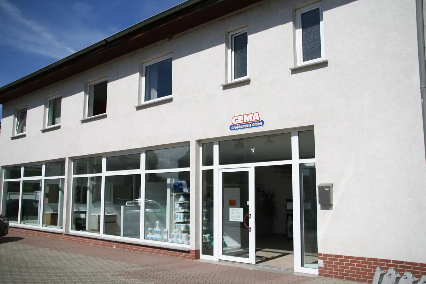 Mehrstöckiges weißes Gebäude mit Schaufensterfronten.